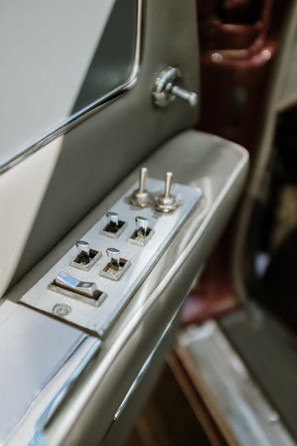 Detailed view of a vintage car door control panel with switches and handle.